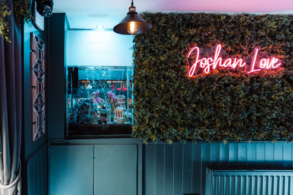 Joshan Love neon sign on green foliage wall at Joshan of Wye, Ashford