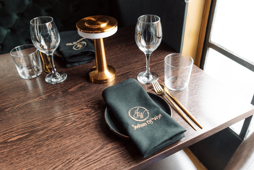 Table setting with wine glasses and Joshan of Wye branded napkin, Ashford